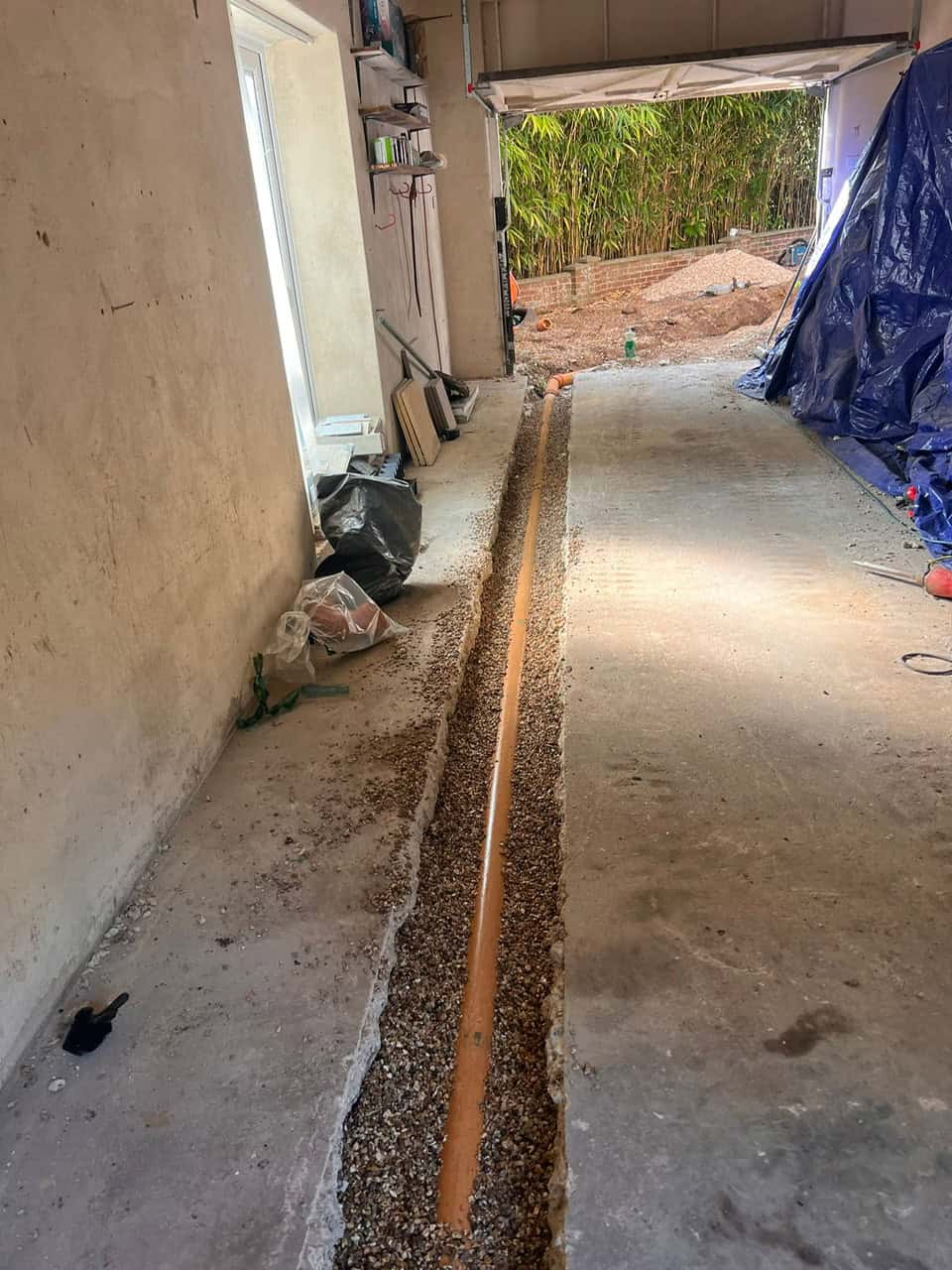 Installing a drainage system with a long pipe in a garage or workshop.
